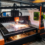 Operator monitors a laser cutting machine in a factory, sparks flying as the torch cuts a metal sheet.